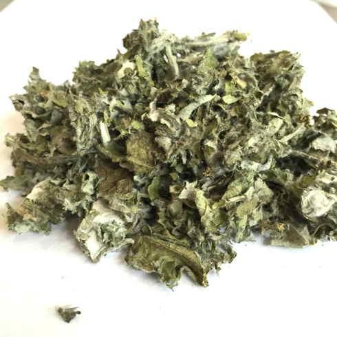 Foglie di carciofo essiccate e sminuzzate per tisana, su sfondo bianco.